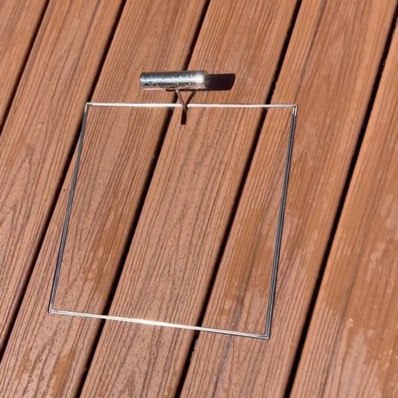 Stainless steel HIDE Access Cover in timber decking with HIDE Safety Key resting in key hole.