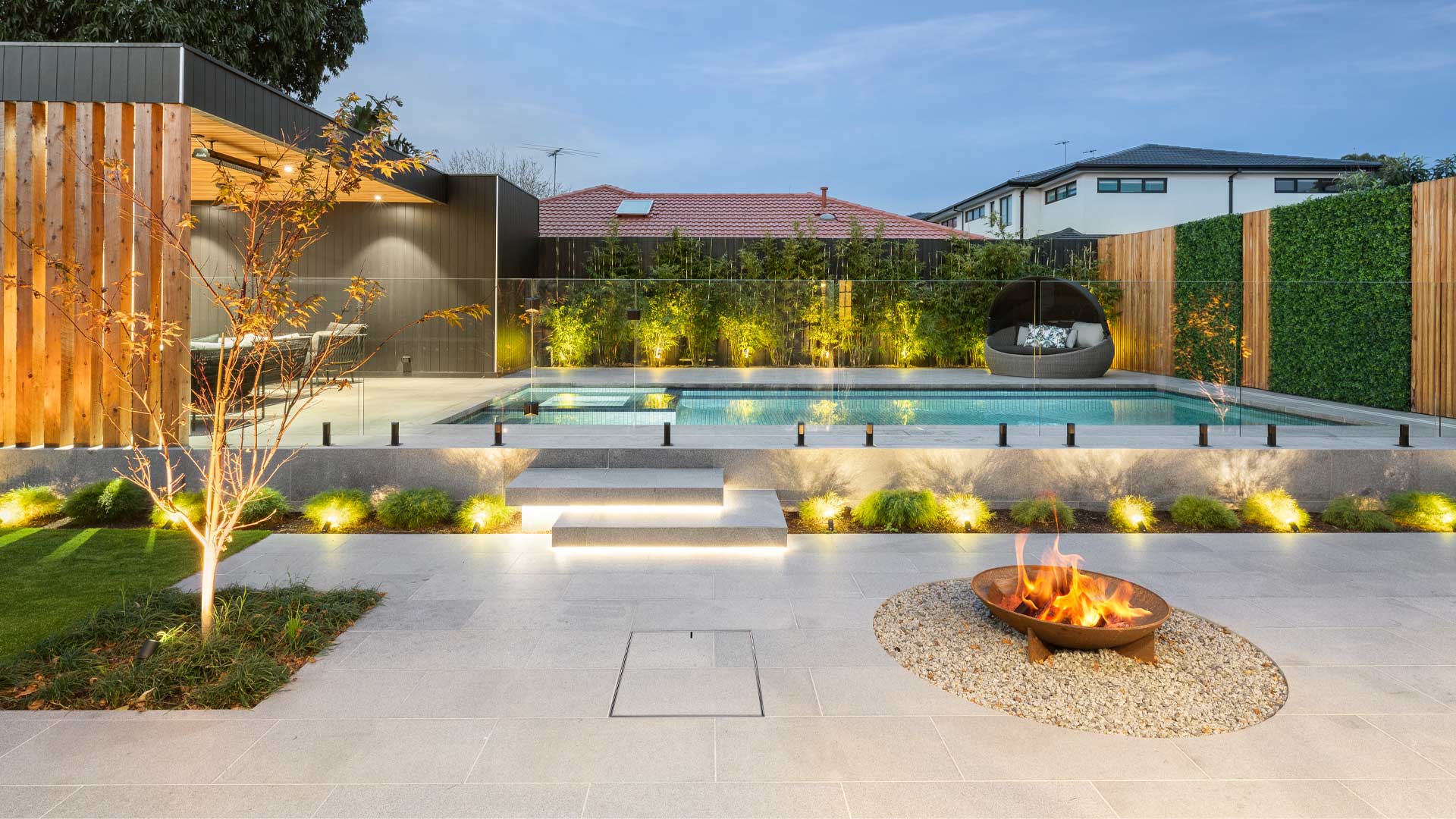 Modern backyard with pool, fire pit, and garden lights. HIDE Access Cover with paving inlay