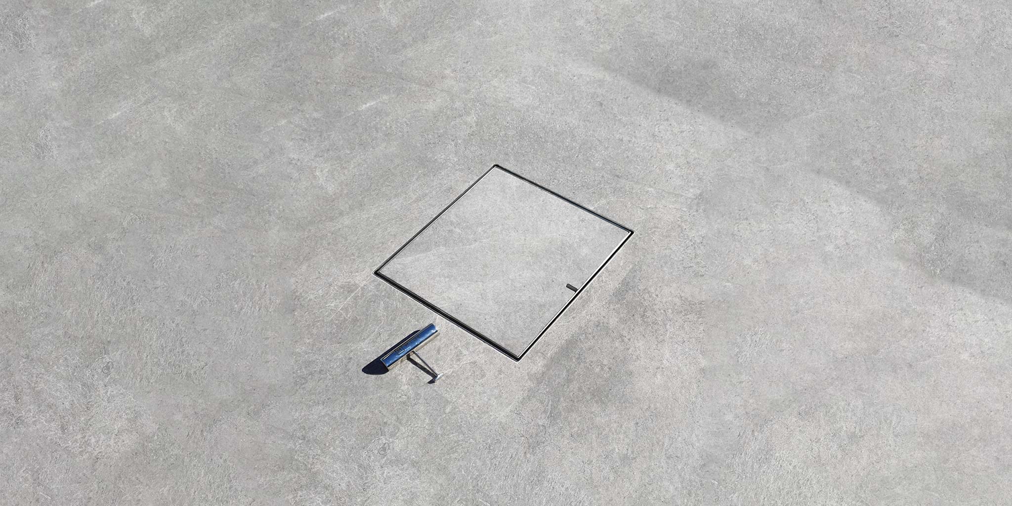 HIDE Concrete Drain Cover with safety key. Grey concrete inlay creating a sleek landscape.