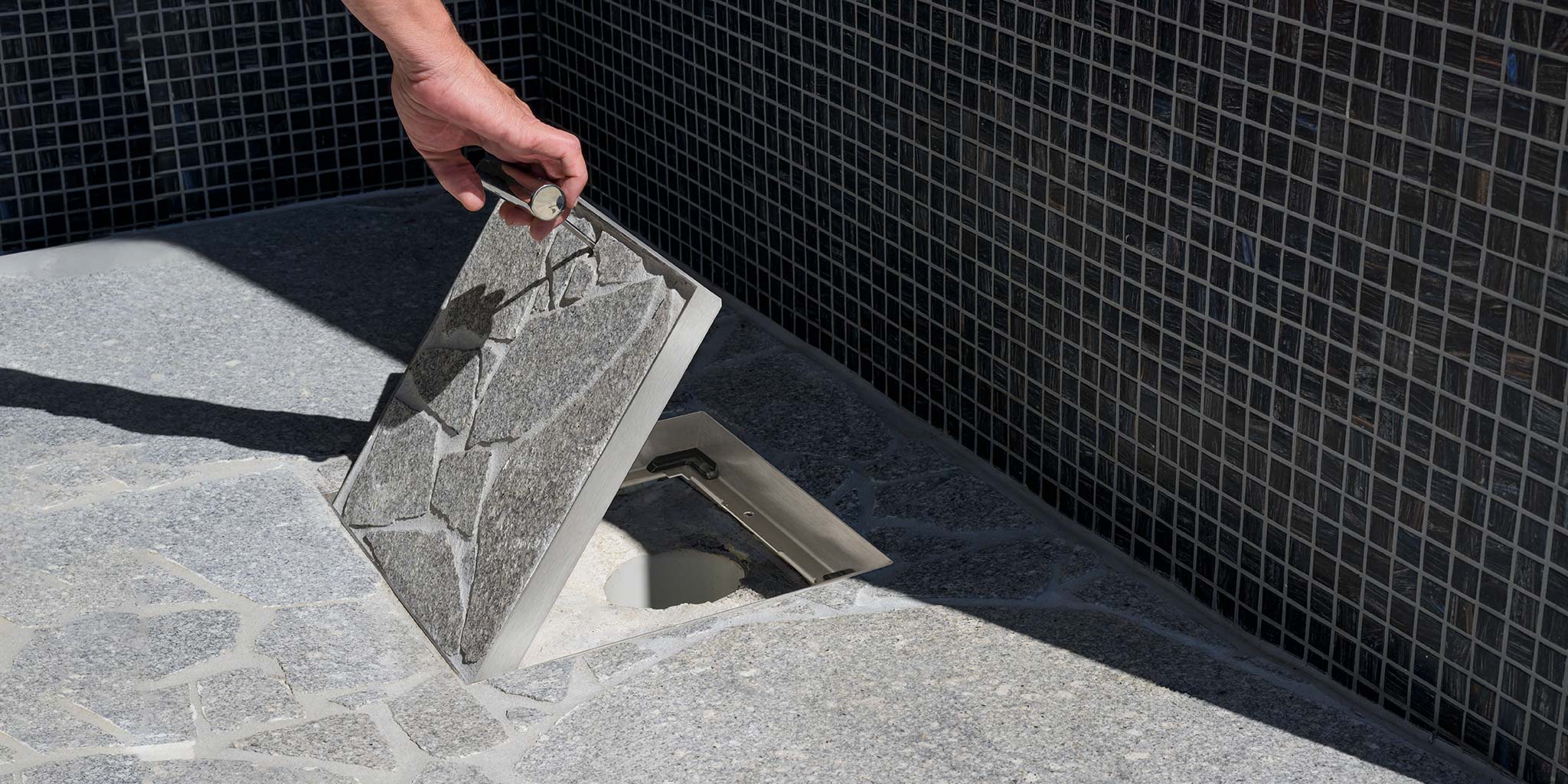 HIDE Drain cover being lifted by HIDE safety key inside outdoor shower.