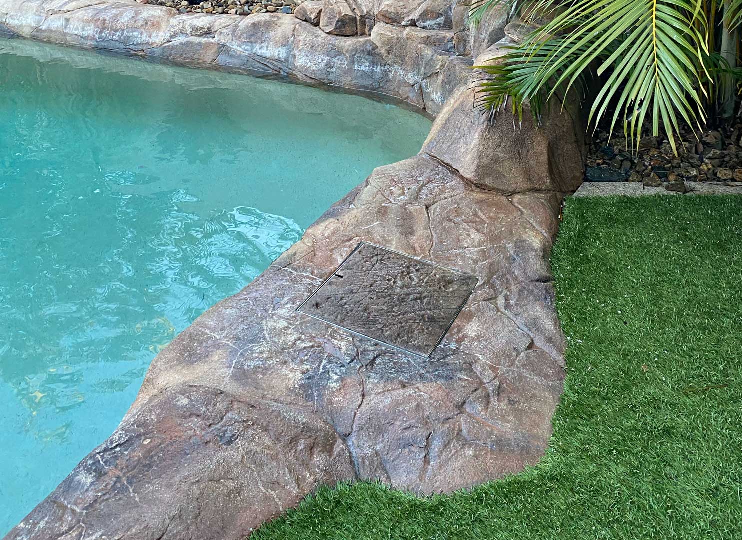 HIDE Skimmer Lid with artificial rock inlay to continue the artificial rock surrounds around a tropical poolscape.