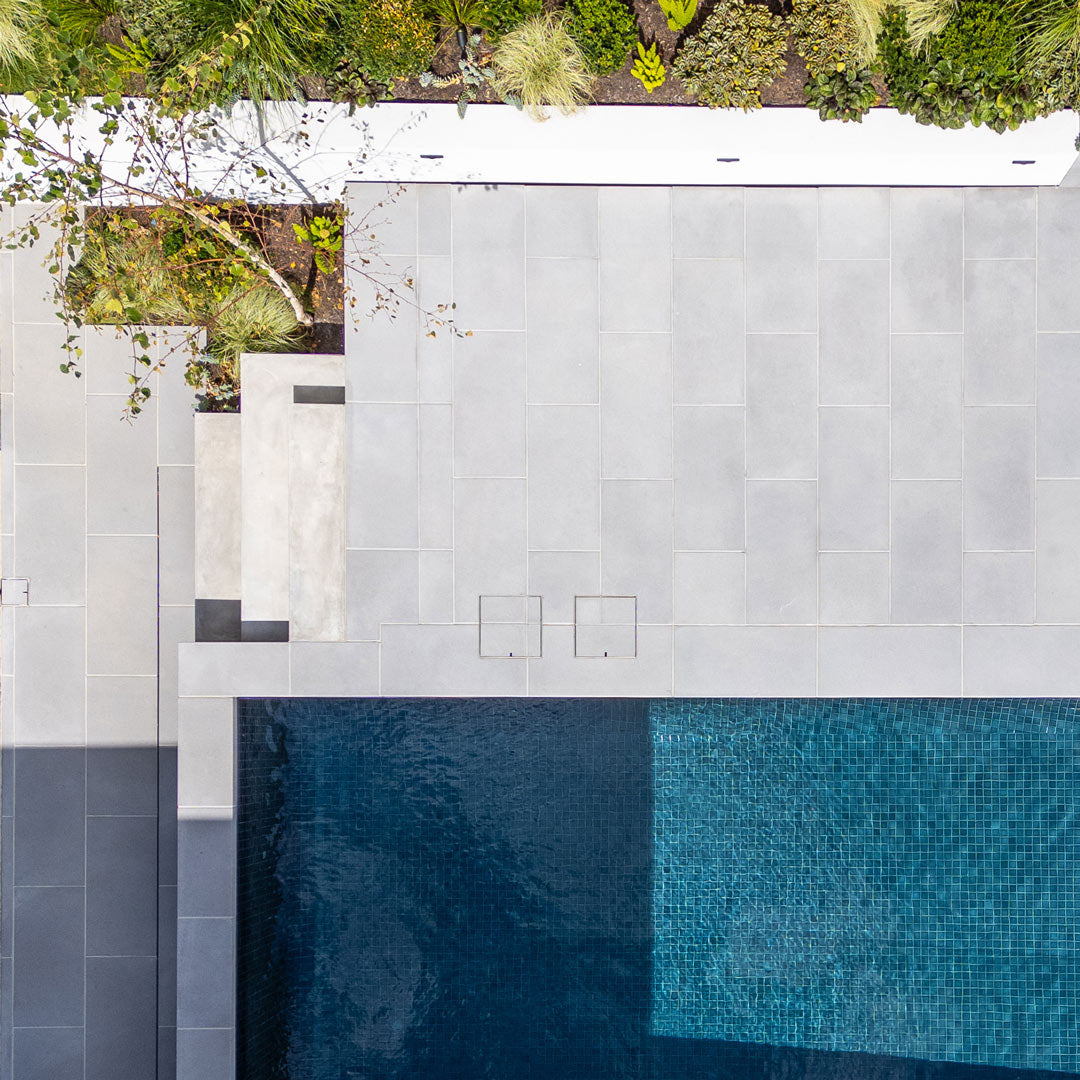 Two concealed HIDE skimmer covers integrated into pool surround pavers, top-down view.