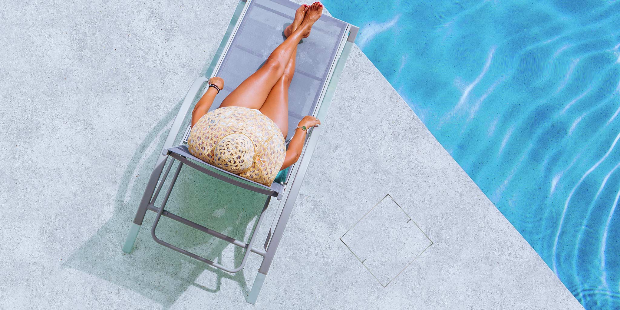 Woman sunbathing on a lounge beside a pool with a flush-fit HIDE inlay cover set into the concrete.