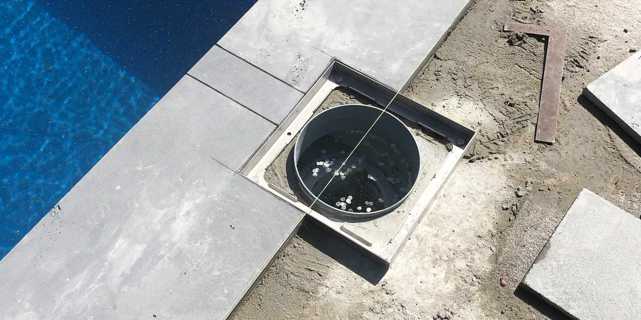 Setting the HIDE inlay cover frame to finished level beside pool coping before tiling. Lining up the pool coping to be in line with the HIDE Cover