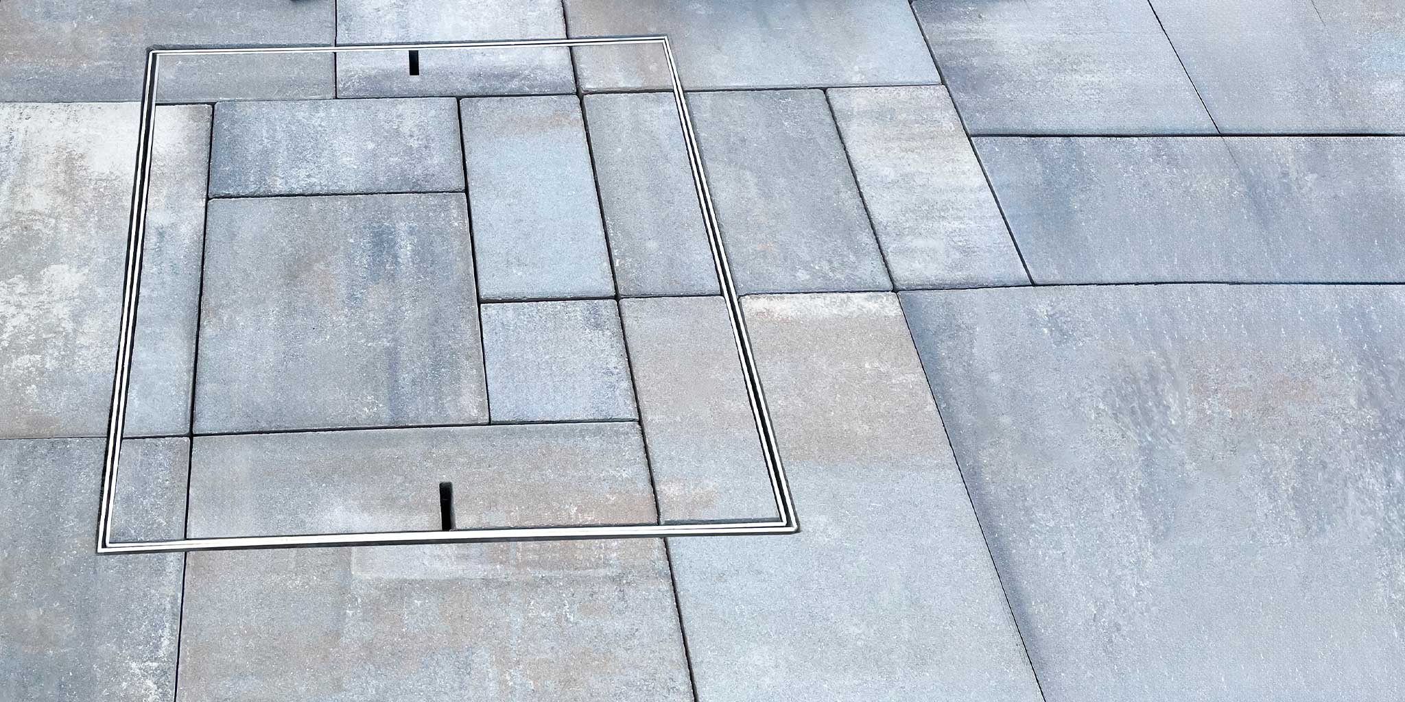Flush-fit HIDE stainless steel Manhole Cover with pavers cut and laid inside, blending into the surrounding patio.