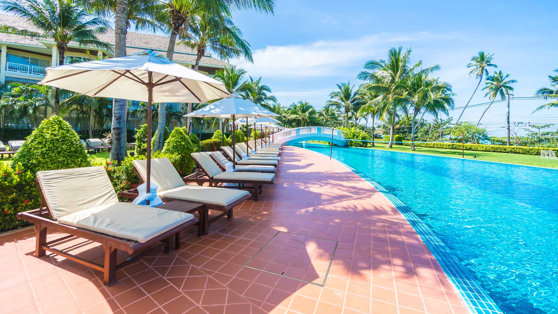 Poolside area with lounge chairs at a resort, a large HIDE Access Cover is hidden in the tiling covering a service access point.