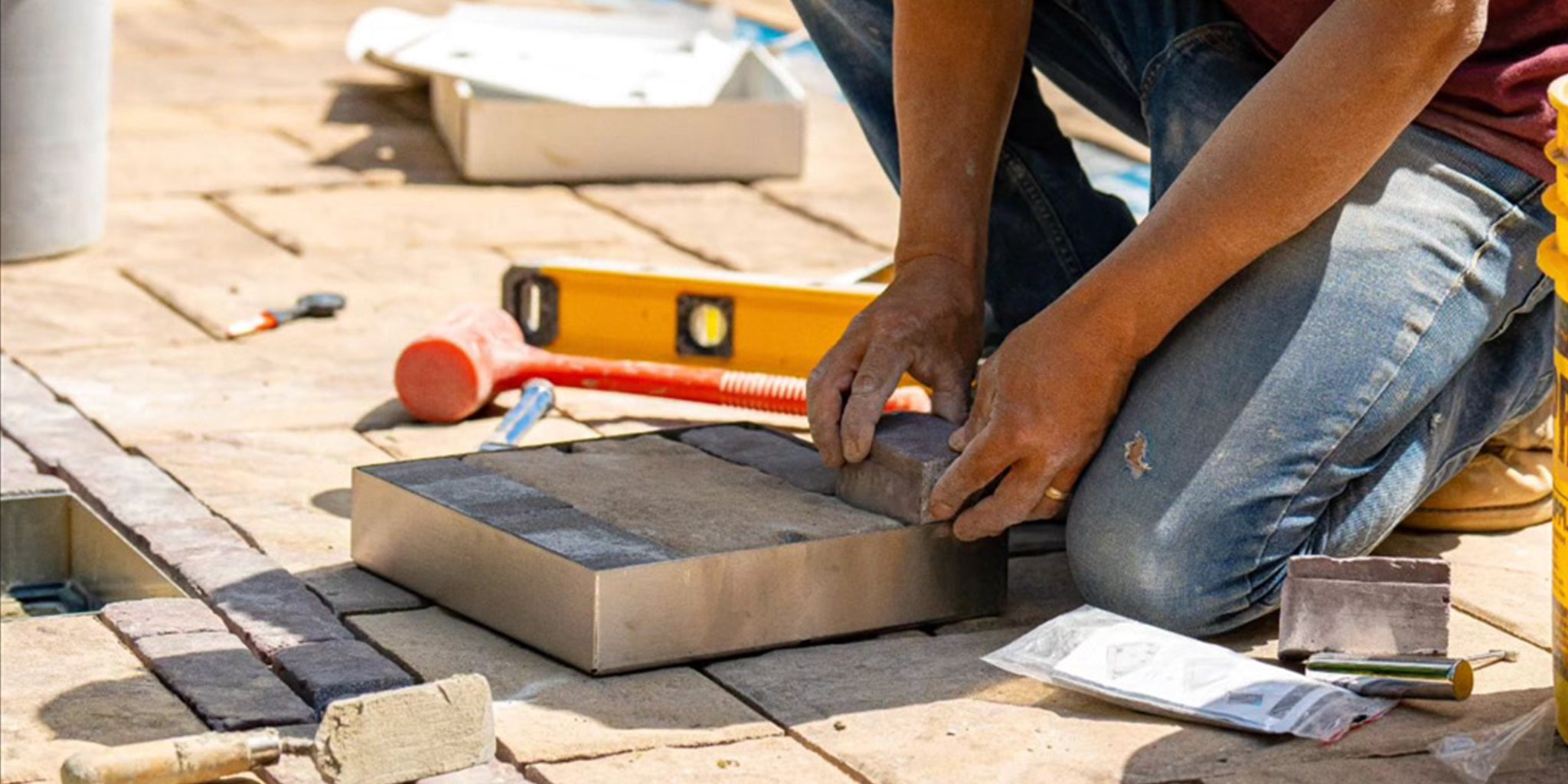 Man installing a HIDE Skimmer Lid, he is placing the pavers into the HIDE Cover that match the surrounding paving pattern.